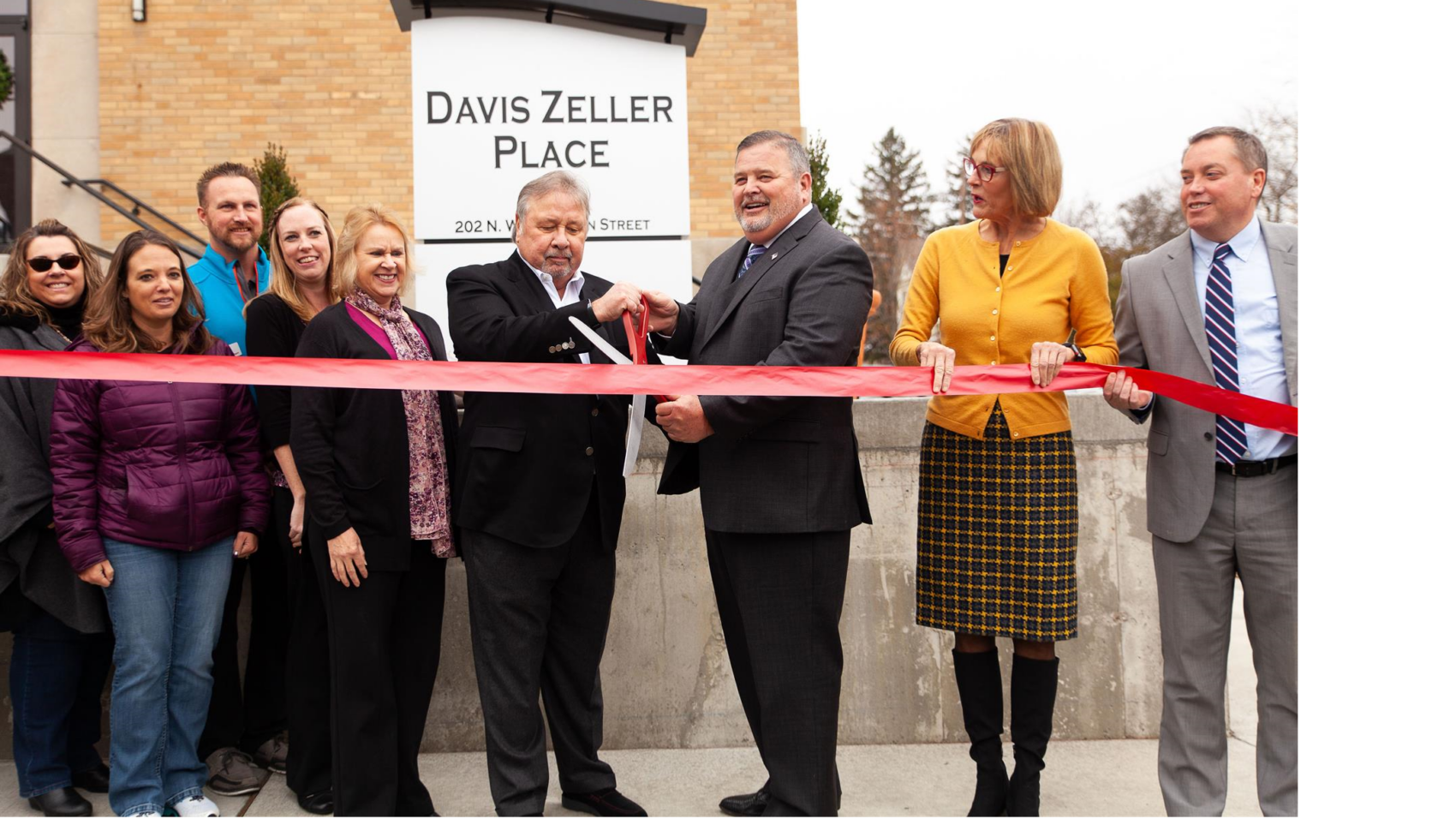 Group cutting ribbon for opening of Davis Zeller Place