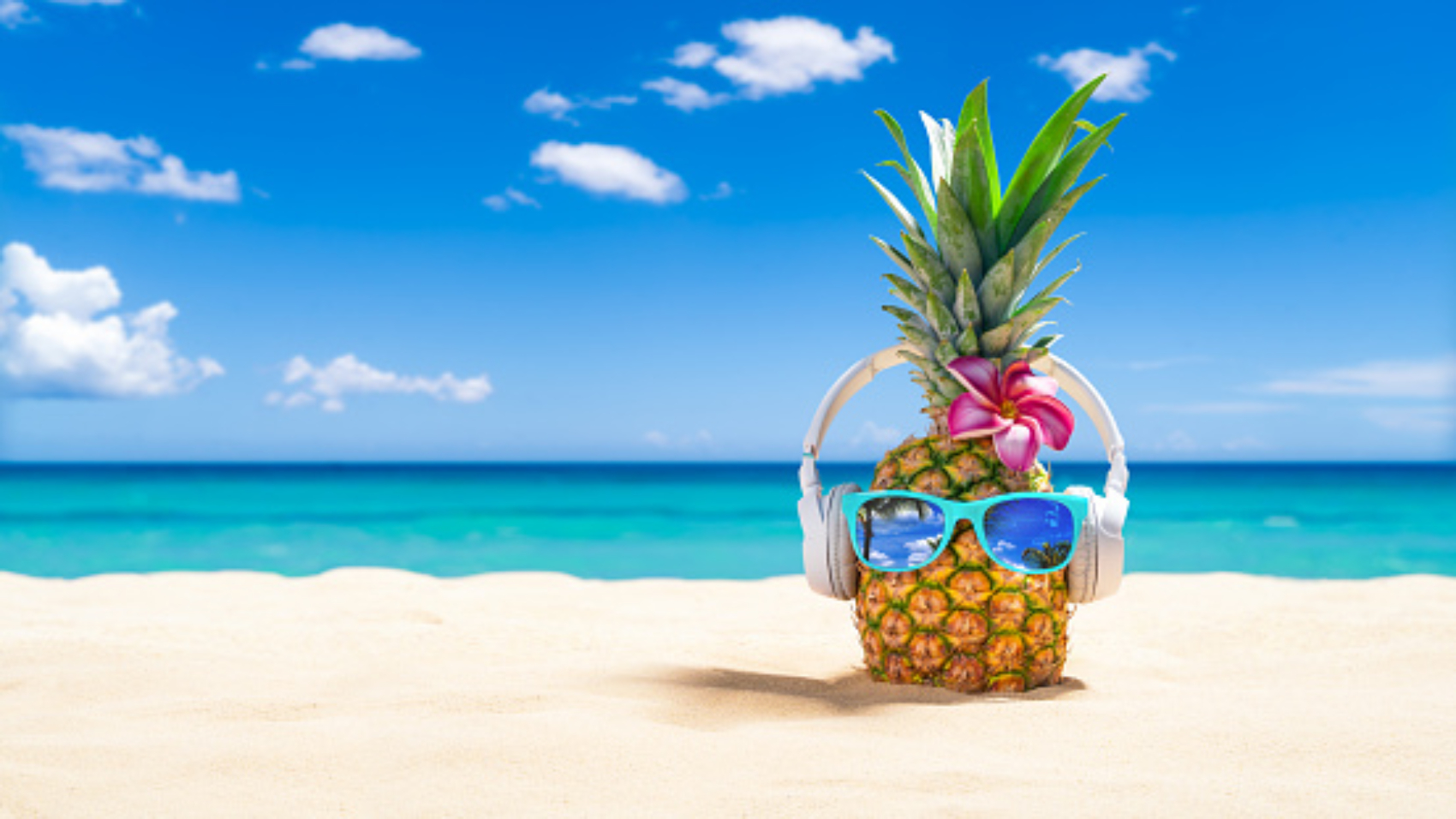 Pineapple on the beach wearing headphones and sunglasses